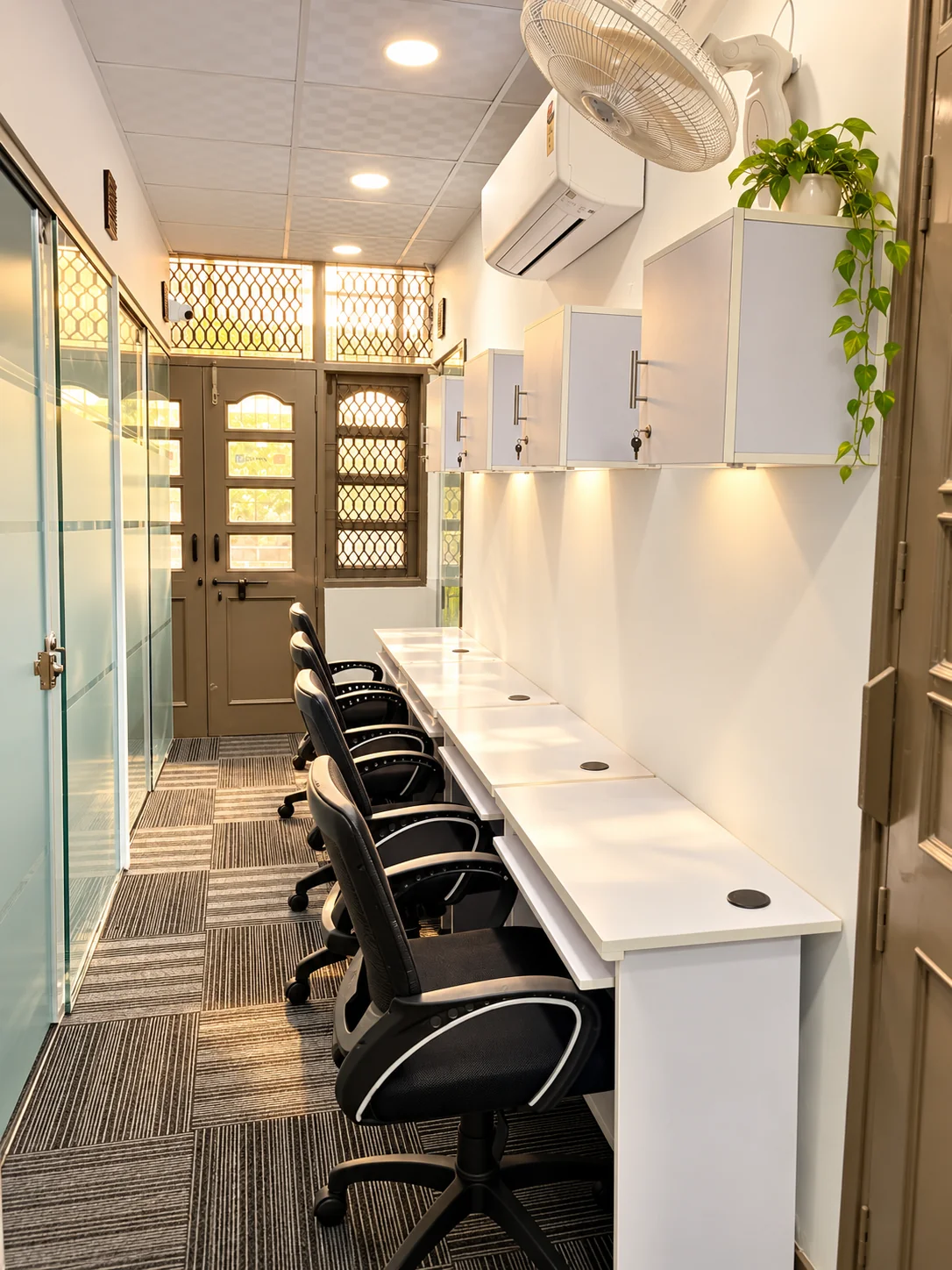Open workstations with personal overhead lockers at Dansa Coworks, Rohini
